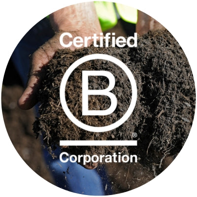 A photo of a hand holding rich soil, with a white B Coporation logo placed over the top.